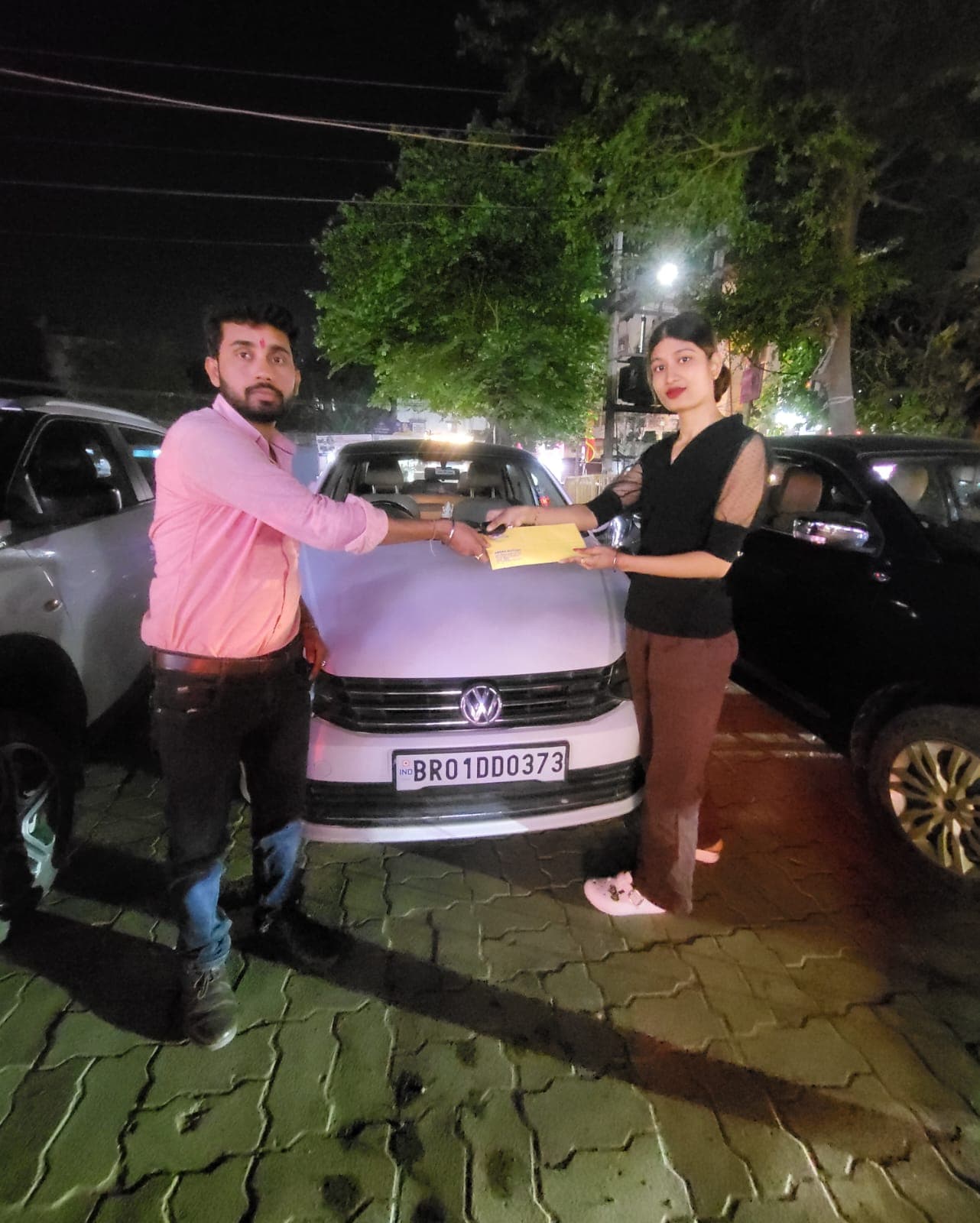 Volkswagen sedan key handover to smiling customer at night